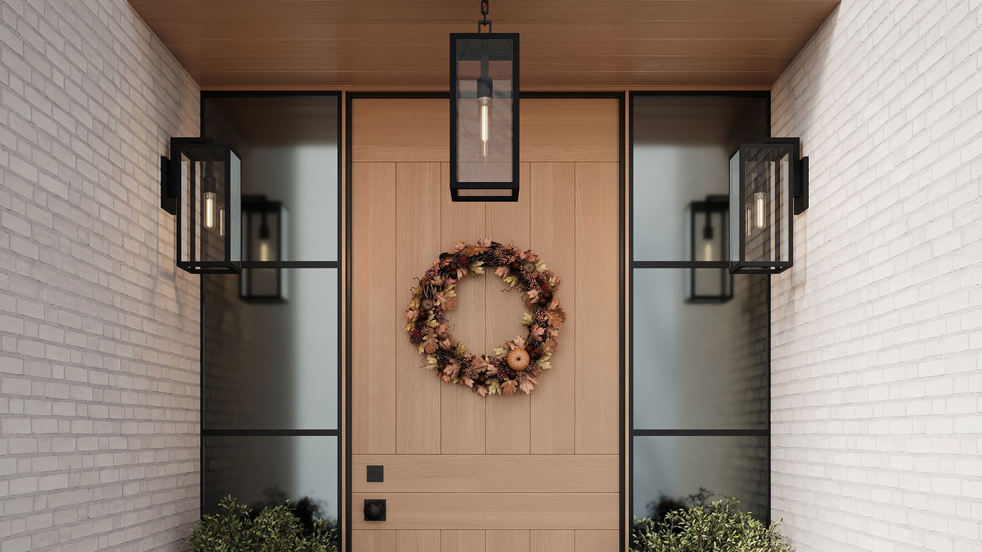 Decorative autumn wreath on a wooden door with modern Sam Outdoor wall lights and hanging light and white brick walls.