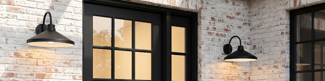 Two modern barn lights in matte black flanking a door on a white brick house.