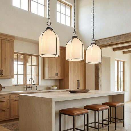 A farmhouse kitchen features three Lana Pendant 14 inch Old Bronze and Opal Glass pendants over a stone island with leather stools under a double-height beamed ceiling.