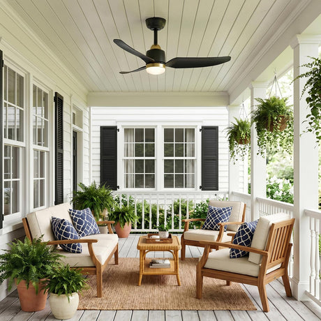 A modern farmhouse porch with white siding and the Kent LED Outdoor Ceiling Fan with Light 42", Brushed Brass and Matte Black on a ceiling with potted ferns.