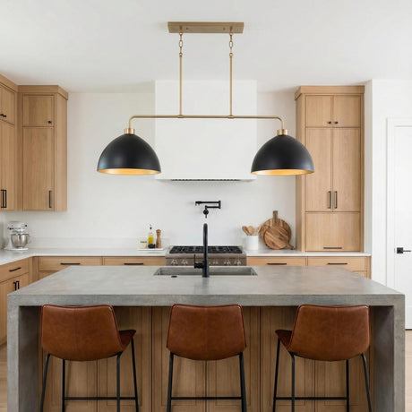 A modern kitchen featuring the Cleo 2 Light Linear Pendant 44", Matte Black and Aged Brass over a concrete waterfall island with wood cabinets and leather barstools.