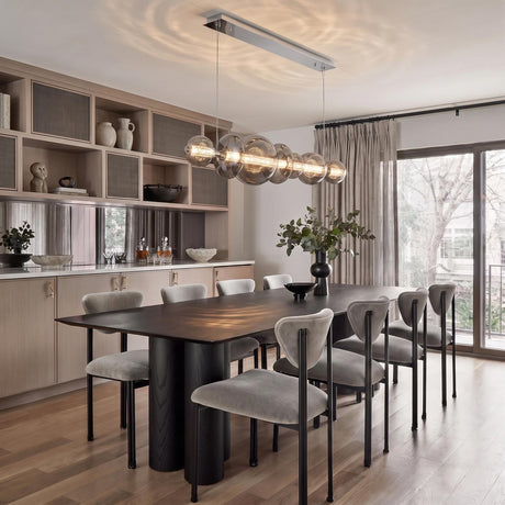 A contemporary dining room with the Elara LED 7 Light Linear Chandelier 56", Chrome and Smoke Glass over a dark wood table and gray chairs.
