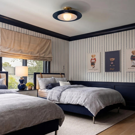 A traditional bedroom featuring the Yates LED Flush Mount 18", Matte Navy on the ceiling center above pinstripe wallpapered walls and twin herringbone beds.