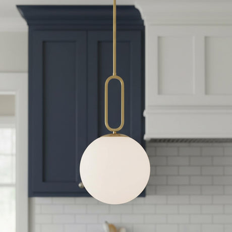 A transitional kitchen features the Oren Pendant 12", Brass and Opal Glass along the perimeter near navy blue cabinets and a white subway tile backsplash.