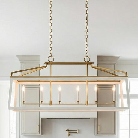 A modern kitchen features the Fillmore Linear Lantern Pendant 48", Matte White and Modern Brass over the island, framed by grey shaker cabinets and a white range hood.