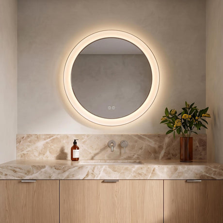 A modern bathroom with the Hedley Round LED Mirror 24" x 24", Polished Nickel mounted above a tan marble countertop and light oak vanity cabinets.