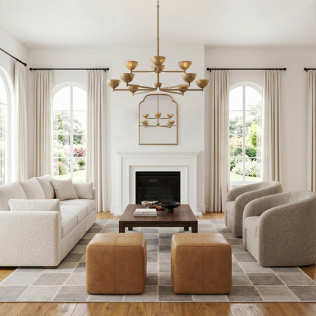 A transitional living room featuring a feathered brass chandelier centered over a dark wood coffee table, flanked by arched windows and tan leather ottomans.