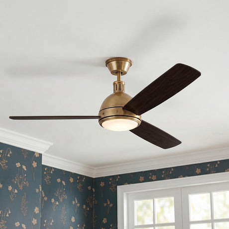 A traditional bedroom featuring the Brant LED Ceiling Fan 60" in antique brass and mahogany wood blades at the ceiling center above blue floral patterned wallpaper.