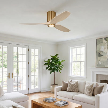A modern living room with a modern brass and whitewash oak ceiling fan installed at the ceiling center above white sofas and a burl wood coffee table.