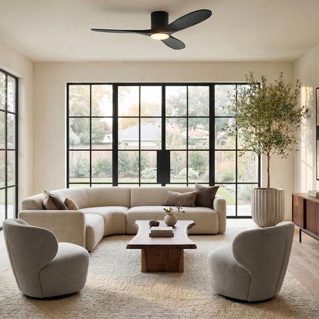 A modern living room with the Eider LED Ceiling Fan 52 inch in matte black oak mounted centrally over a beige sectional and live-edge wood table.