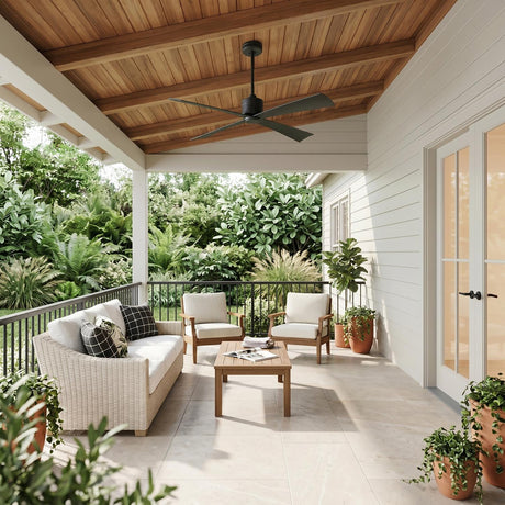 A modern porch with a matte black Sora Ceiling Fan 56" installed on a natural wood plank ceiling above a wicker sofa and white siding.