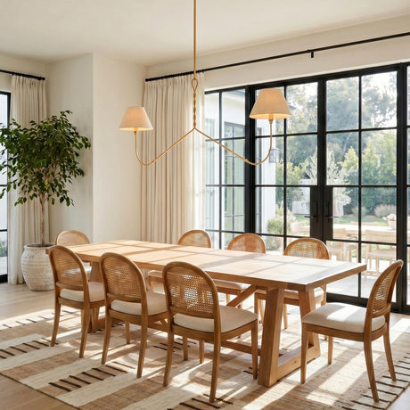 A transitional dining room featuring the Thornton Linear Pendant 60 inch in gold leaf over a wood table with cane chairs and black framed doors.