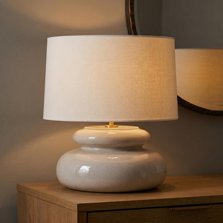 A transitional foyer with the Ellsworth Table Lamp 20", Taupe Crackle Ceramic on a light wood console table beside a round bronze framed mirror.