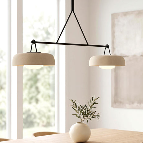 A modern dining room featuring the Stratford 2 Shade Linear Pendant in aged iron and beige over a light wood table with a white ceramic vase.